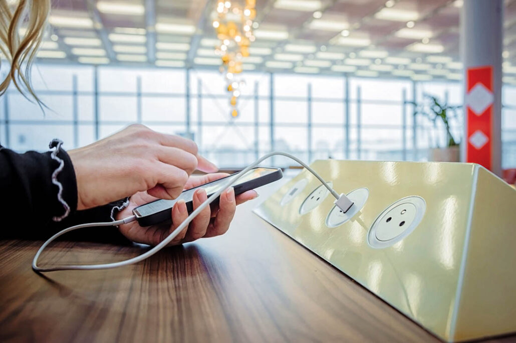woman charging her cell phone at an airport charging bank