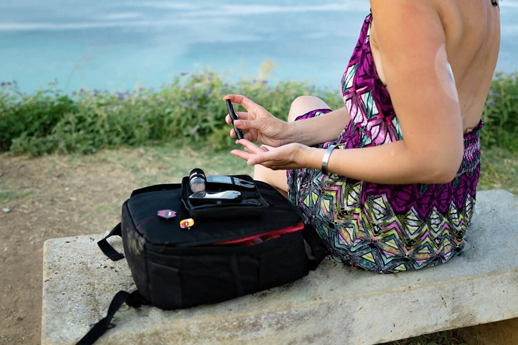 Woman with diabetes testing her blood sugar at the beach