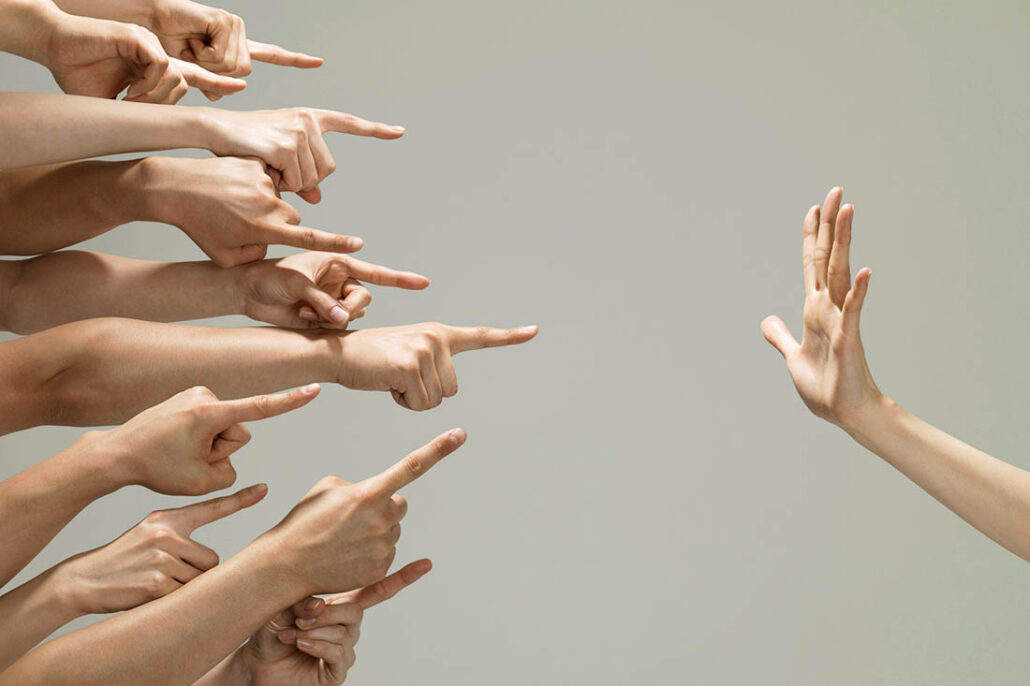 Fingers pointing blame at someone, with a hand signifying to stop