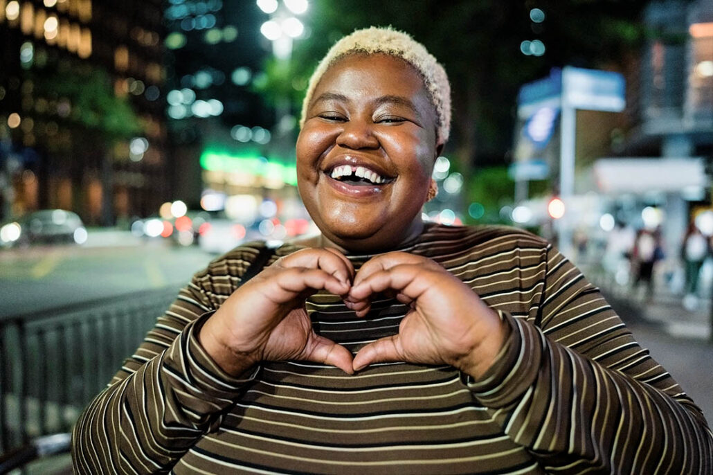 A woman making the shape of a heart with her hands, representing someone taking care of heart health