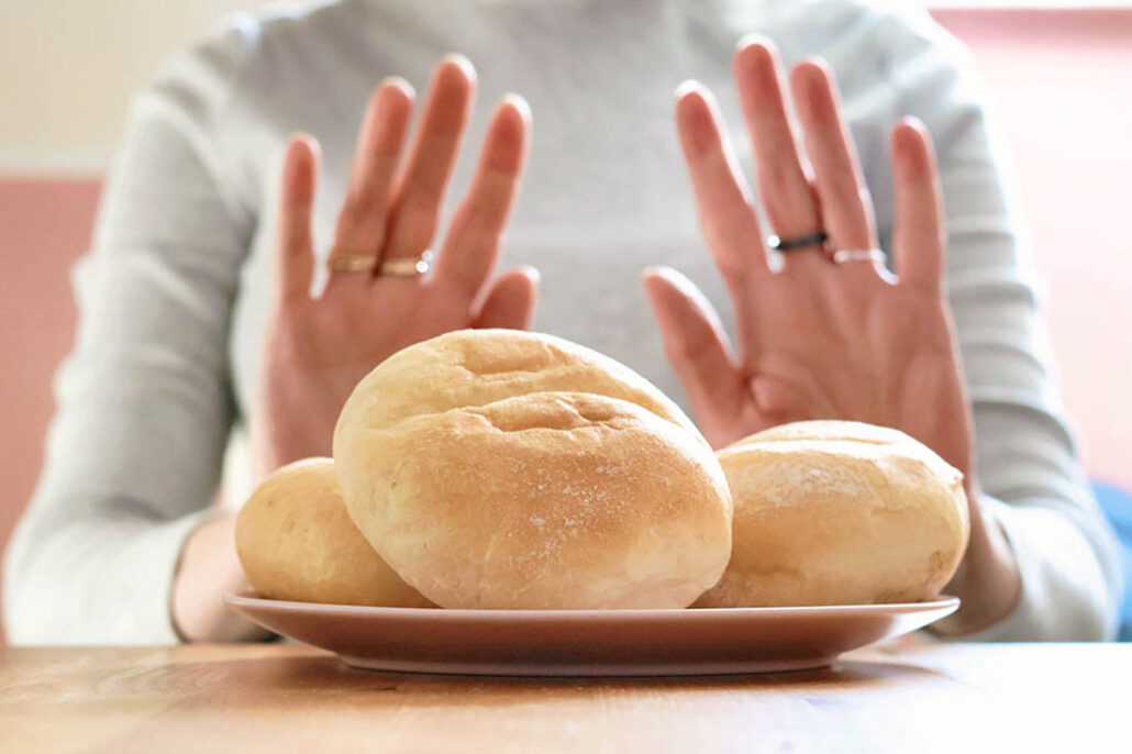 woman pushing bread away due to celiac disease and gluten intolerance