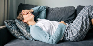 Woman with headache and stomach ache laying on the couch