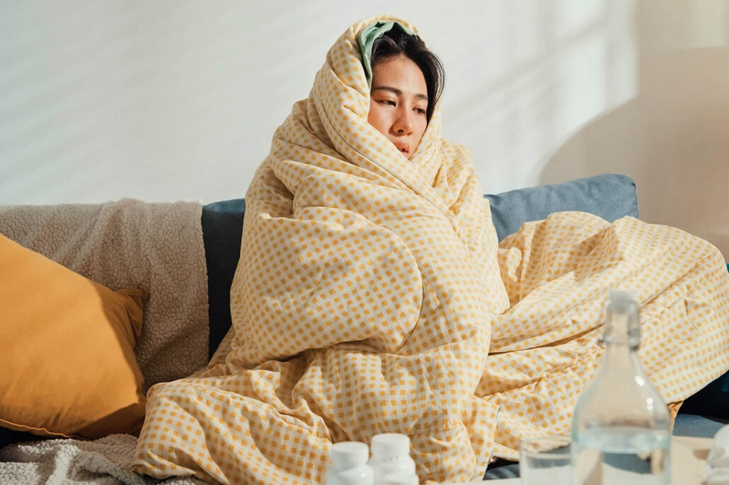 Woman wrapped in a blanket sick on the couch