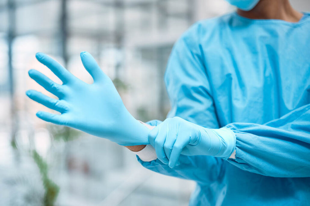 A doctor puts on latex gloves before giving a prostate exam
