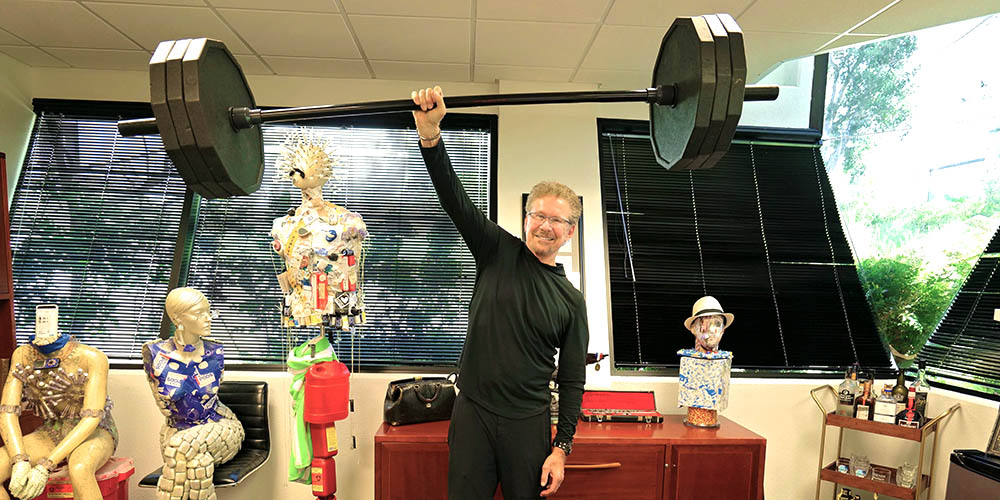 endocrinologist Dr. Steve Edelman pumping weights with one hand in his office
