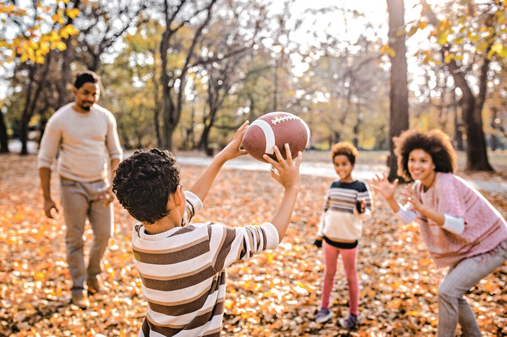 Young family throwing the football around in park on Thanksgiving