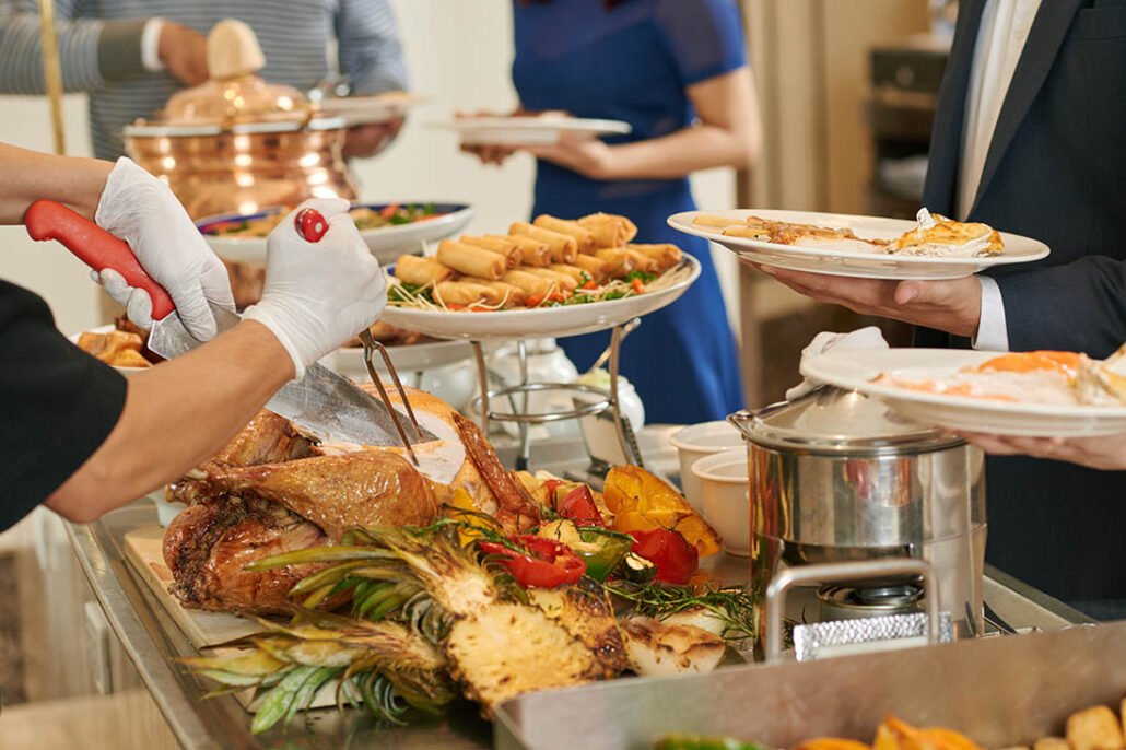 People filling their dinner plates in a Thanksgiving buffet line