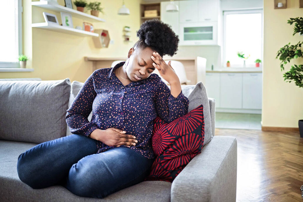A woman on the couch with a headache and stomach ache indicating diabetic ketoacidocis