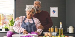 A slightly overweight attractive middle-aged biracial couple cook in the kitchen together