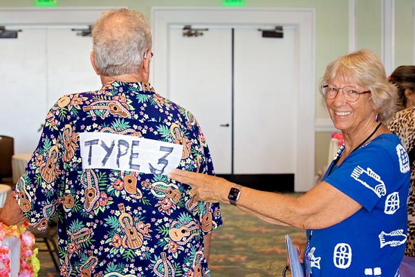 A woman points to a sign on a man's back that says, "Type 3"