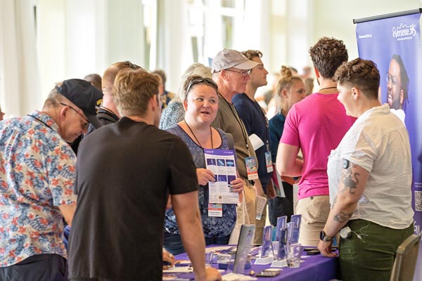 Several people stand in front of a table at a health fair speaking to a vendor