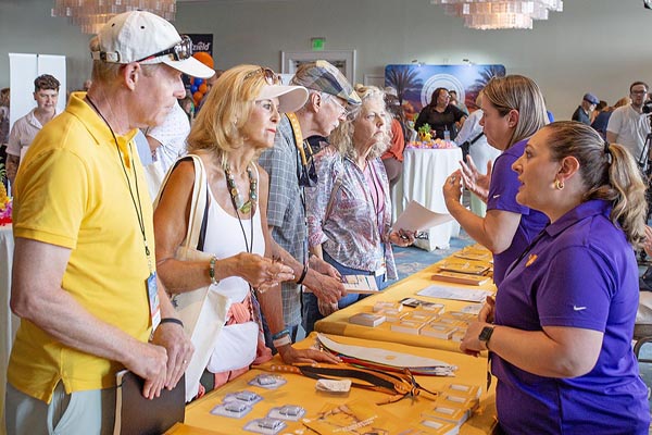 An older couple stand in front of a table at a health fair speaking with a vendor