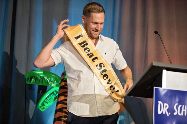 A man wears a sash that says, "I beat Steve"