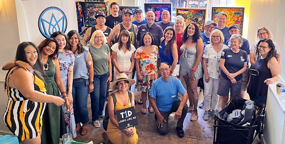 Group of people of different ages at an art gallery, one holding a sign that says T1D Looks Like Me